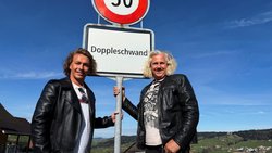 Martin Schwar­zentruber (l.) und Christian Duss zeigen sich stolz mit der Ortstafel ihrer Heimat­gemeinde.