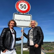 Martin Schwar­zentruber (l.) und Christian Duss zeigen sich stolz mit der Ortstafel ihrer Heimat­gemeinde.
